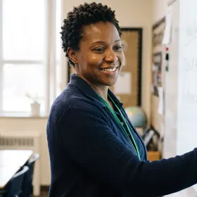 A teacher at a classroom whiteboard, wearing an Elevate Grade lanyard